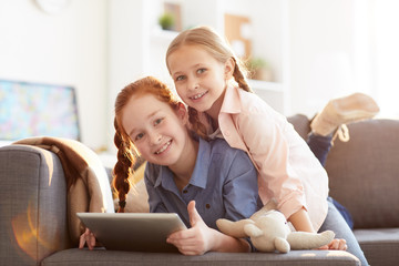 Portrait of two happy loving sisters looking at camera while having fun at home in comfort, copy space