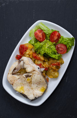 boiled fish with vegetables and fresh salad on white dish