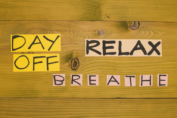 Image of text day off,relax and breathe on wooden table.Toned photo.