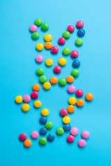 close up of chocolate egg and candy drops rabbit on blue background