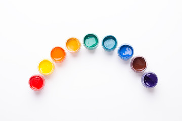 Multicolored gouache on a white background Rainbow shape Isolated Paints in containers Top view