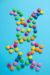 close up of chocolate egg and candy drops rabbit on blue background