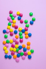 close up of chocolate egg and candy drops on pink background
