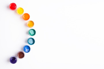 Multicolored gouache on a white background Rainbow shape Isolated Paints in containers Top view Banner Horizontal