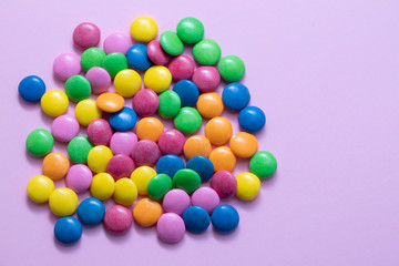 close up of chocolate egg and candy drops on pink background