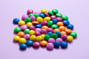 close up of chocolate egg and candy drops on pink background