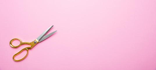 Scissors with golden handle on pink background, banne, copy space, top view