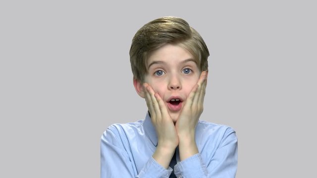 Portrait of frightened child boy. Shocked scared little boy screaming against gray background. Human expression of fear.