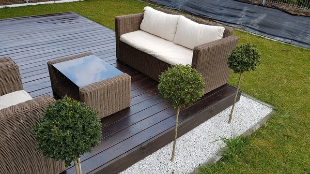 Meble ogrodowe na drewnianym tarasie w słoneczny dzień, relaks na świeżym powietrzu