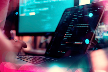 Web or application development, technology concept, neon light. Programmer, man software developer hands coding HTML, programming Javascript on laptop computer screen, back view close up