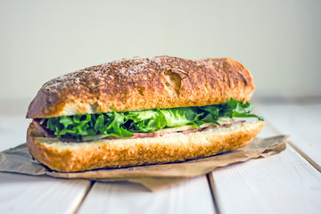 Closed sandwich with greens, ham and cheese. Close-up, copy space