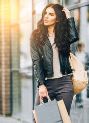 Young pretty latin woman walking near shops in city centre