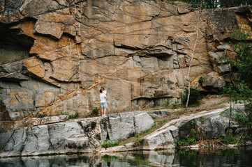 Man picked up on hands woman, hugs, kissing  on the background of rocks. Landscape of an old industrial granite quarry. Canyon. Place for text and design. Lake, river. full length
