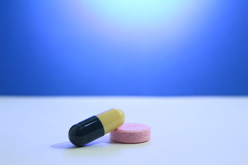 Capsule pills medical, white and pink, on a blue background.