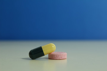 Capsule pills medical, white and pink, on a blue background.