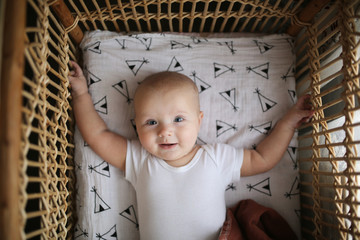 baby lying in wicker crib, top view and emotions
