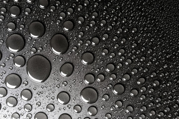 Droplets of water on a black, matte background illuminated with a delicate light.