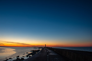 Fototapeta na wymiar dramatic sunset over sea beach with rocks and stormy water