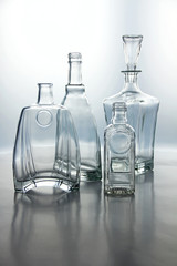 Empty glass bottles. Transparent forms for cold drinks, randomly presented and isolated on a gray background.