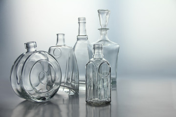 Empty glass bottles. Transparent forms for cold drinks, randomly presented and isolated on a gray...
