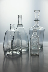 Empty glass bottles. Transparent forms for cold drinks, randomly presented and isolated on a gray background.