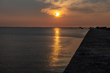 calm sea beach in summer with large rocks and wooden poles from old breakewater in the sea