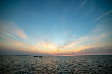 calm sea beach in summer with large rocks and wooden poles from old breakewater in the sea