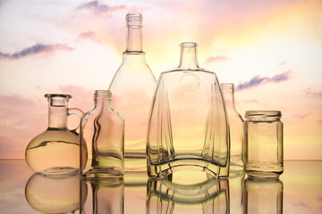 Empty glass bottles. Transparent forms for cold drinks, randomly presented and on a sky background. Presentation of glass forms in the industrial production of glass.