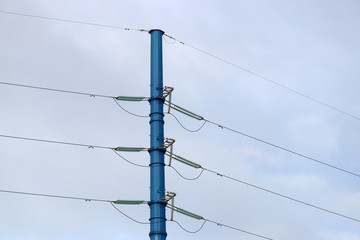 Power line support against blue sky with white clouds. High-voltage electricity transmission line