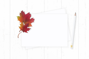 Flat lay top view elegant white composition paper pencil and autumn maple leaf on wooden background
