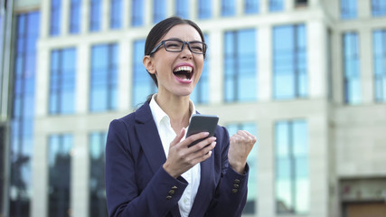 Enthusiastic business woman showing success gesture reading mobile email, career