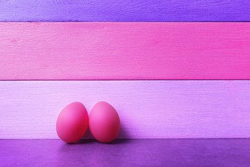 Two pink Easter eggs over violet-pink background.