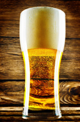 Glass of cold light beer with Easter decorations on a wood background for the Easter holidays