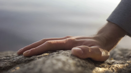 Man climbing mountain, reaching top, active leisure, survival training, hiking