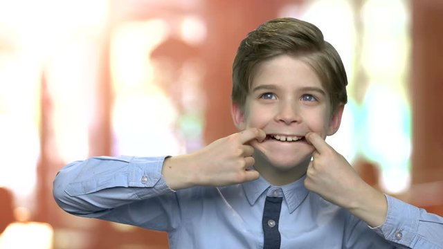 Little caucasian boy making monkey face. Cute child fooling around. Kid making funny grimace.