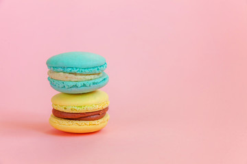 Sweet almond colorful unicorn blue yellow macaron or macaroon dessert cake isolated on trendy pink pastel background. French sweet cookie. Minimal food bakery concept. Copy space