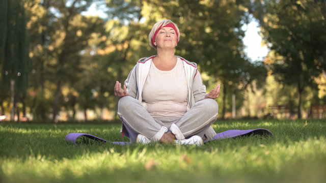 Middle age woman deeply breathing and meditating sitting in lotus position