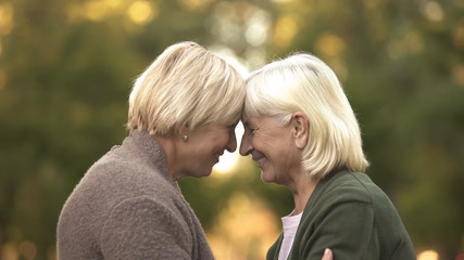 Fototapeta premium Sisters leaning heads outdoor, supporting to each other, warm family relations