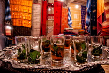 Traditional Moroccan mint tea in a vintage silver tray. Background of colored carpets