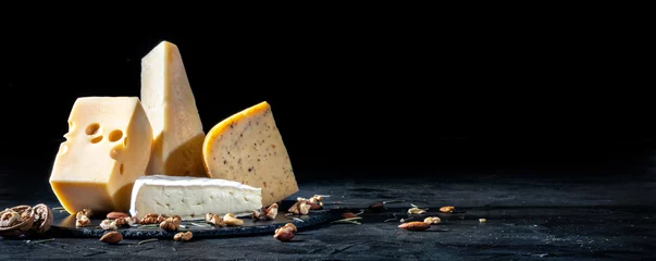 Fotobehang Different kinds of cheese with nuts on dark background, copy space © Andrii