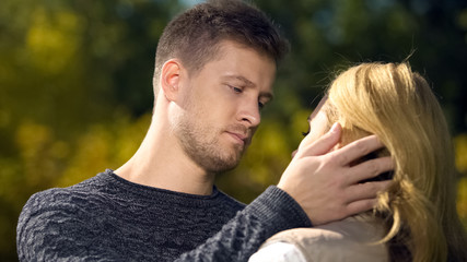 Fototapeta premium Upset man looking at woman and touching her face, lack of money, unemployment