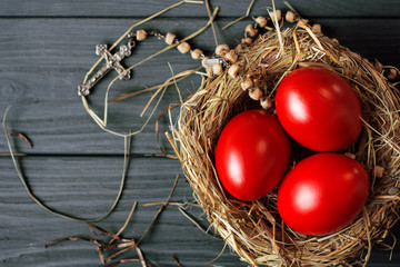 Easter background with dark red Easter eggs in nest and catholic rosary with a cross. Top view with copy space. 