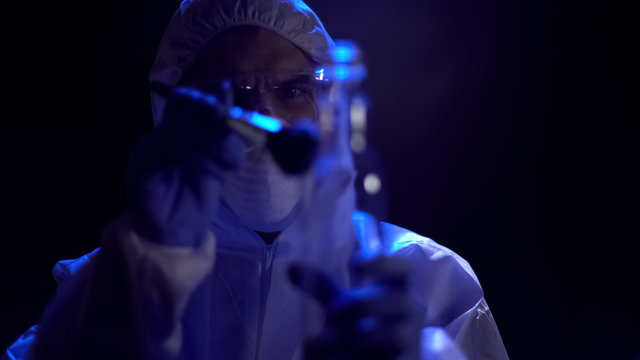 Criminalist taking fingerprints from bottle at crime scene, search for evidence