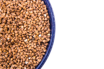 raw buckwheat seeds in the blue bowl on the white background