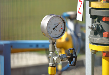 Pressure gauge for measuring the pressure of natural gas in a gas pipeline. Yellow transport pipes on the surface of the fence. Regulatory system for supplying natural compressed fuel.