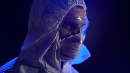 Chemist in lab costume wearing mask, secret manufacture of biological weapon