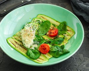 zucchini grilled with tomato and cream cheese, sauce, garlic and microgreen (warm salad snack). food background. copy space