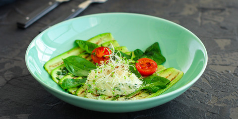 zucchini grilled with tomato and cream cheese, sauce, garlic and microgreen (warm salad snack). food background. copy space