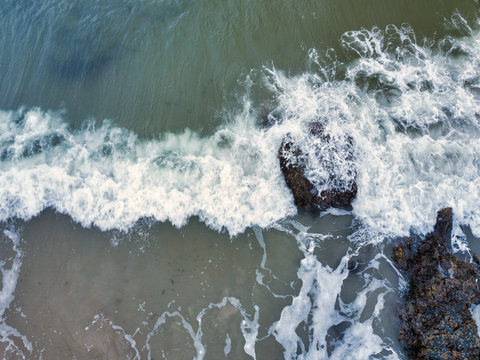 Aerial drone image of a rocky beach on the Maine coast with the waves washing up on the rocks