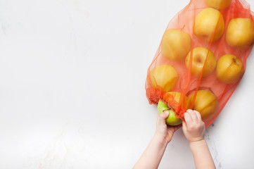 Kids hands taking an apple from eco-friendly shopping bag